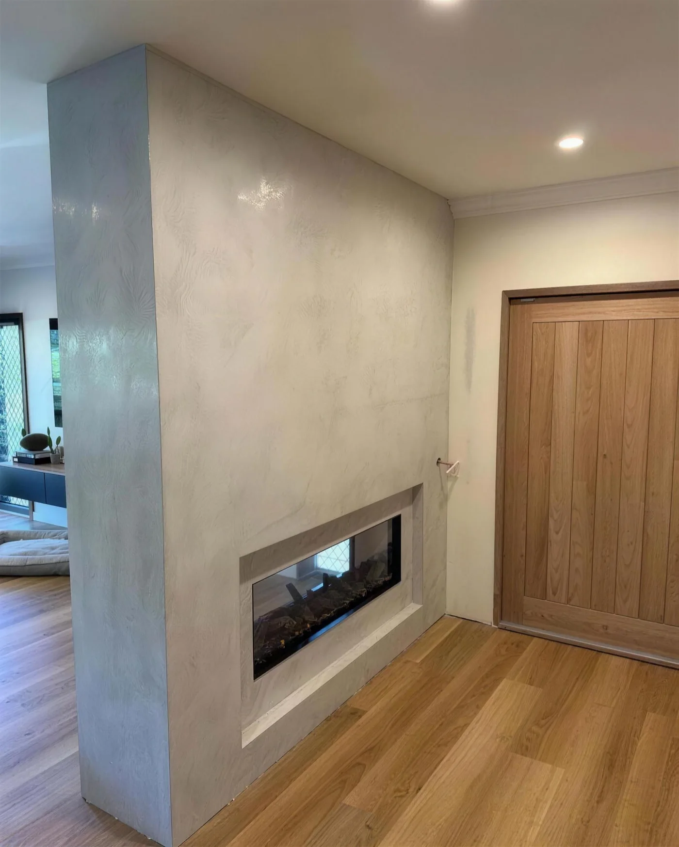 Micro cement fireplace wall beside a timber door