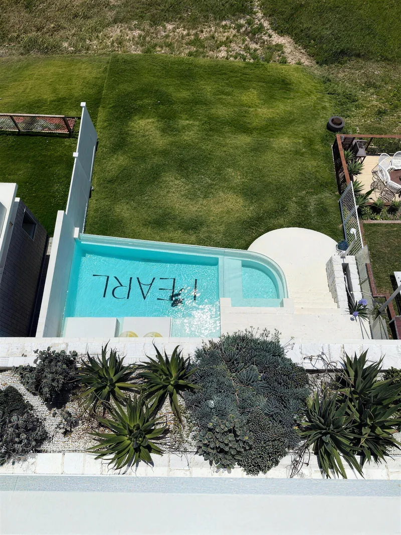 White rendered pool cabana beside a turquoise pool