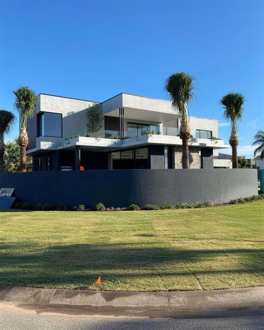 Two-storey home with grey cladding and palm trees